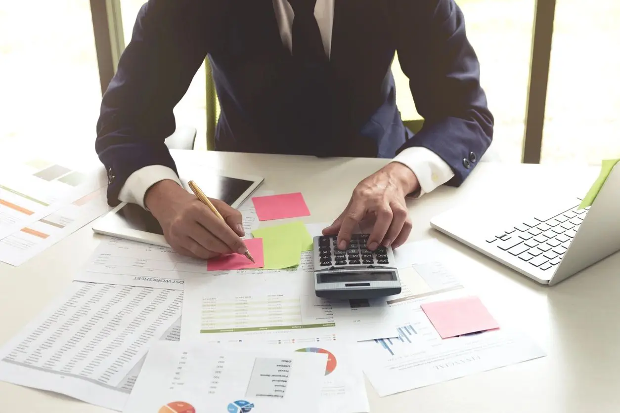 Business Man Analysis on Data Paper Using Calculator and Laptop on White Desk at the Office